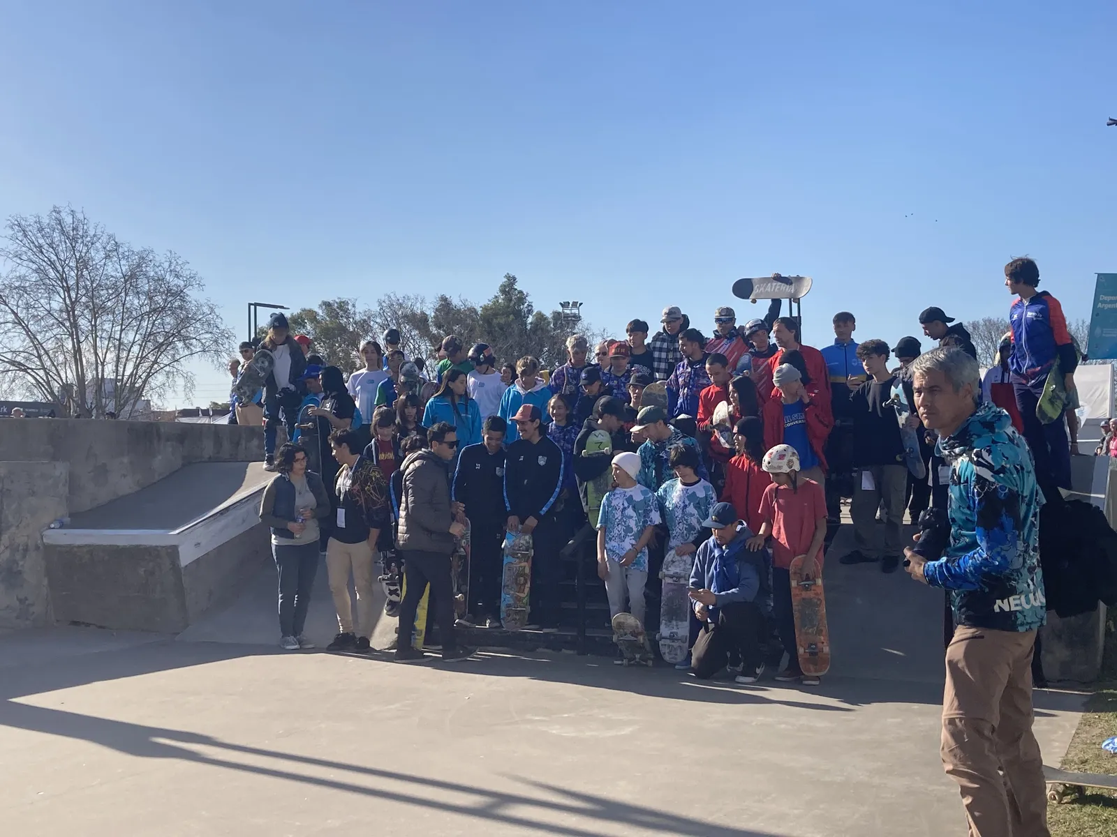 Gran grupo de chicos y chicas con sus tablas en un skatepark